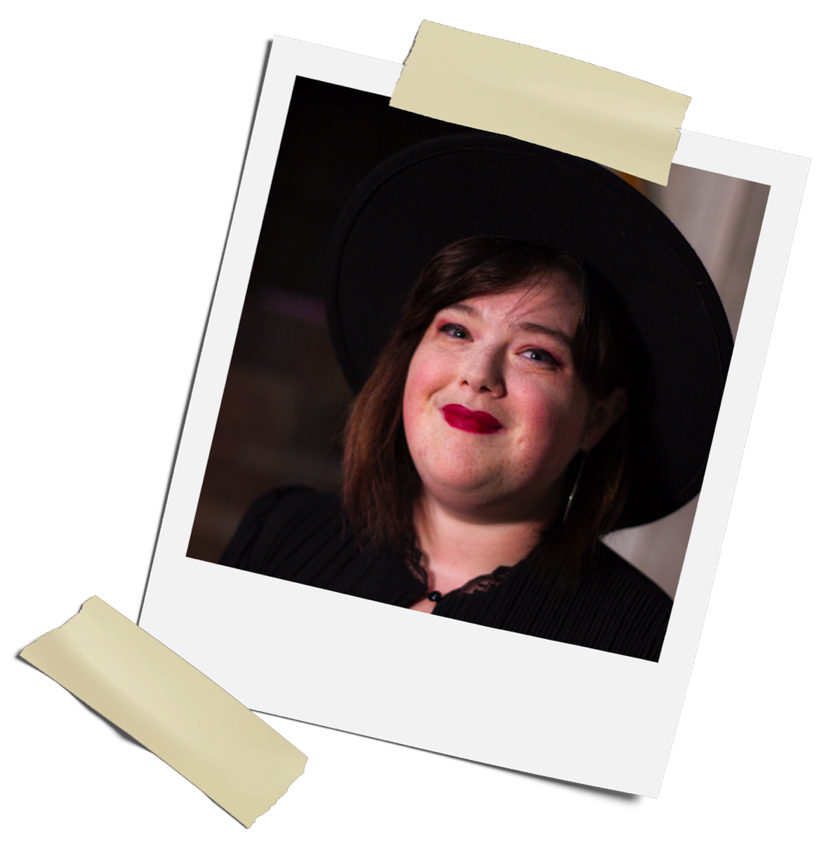 A Polaroid photo of a woman, Sarah, with shoulder length hair. She is wearing a black, wide-brim hat and a black top with a lace collar. She is also wearing bright red lipstick